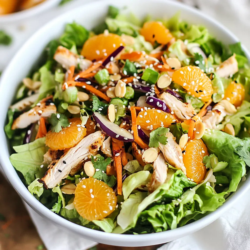 Un bol de salade avec poulet, carottes et quartiers de mandarine.