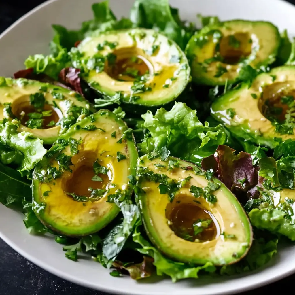 Une assiette blanche garnie de jeunes pousses et d’avocat.