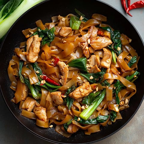 A bowl of food with noodles, meat, and vegetables.