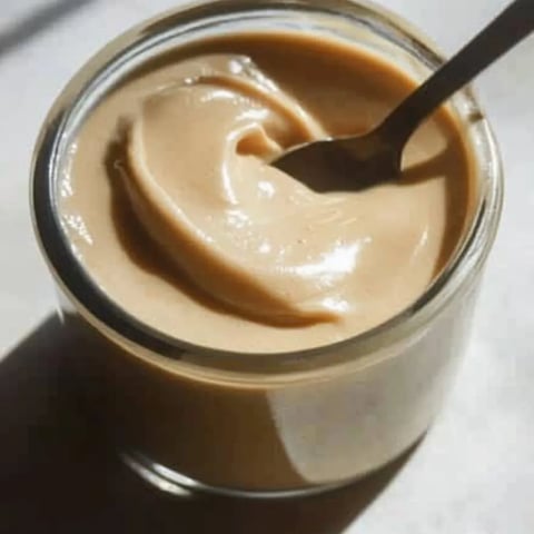Un pot de beurre de cacahuète avec une cuillère dedans.