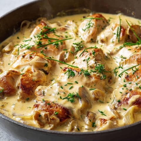 Un bol en métal rempli de poulet nappé d’une sauce crémeuse à la moutarde.