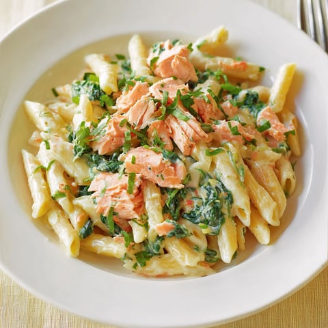 Un plat de pâtes crémeuses au saumon, rehaussé de touche de coriandre et de légumes verts.