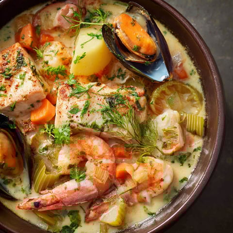 Un grand pot-au-feu de la mer débordant de moules, légumes colorés et carottes.