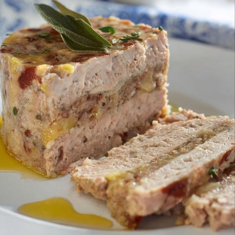 On voit une terrine de volaille présentée sur un plateau avec une sauce à côté.