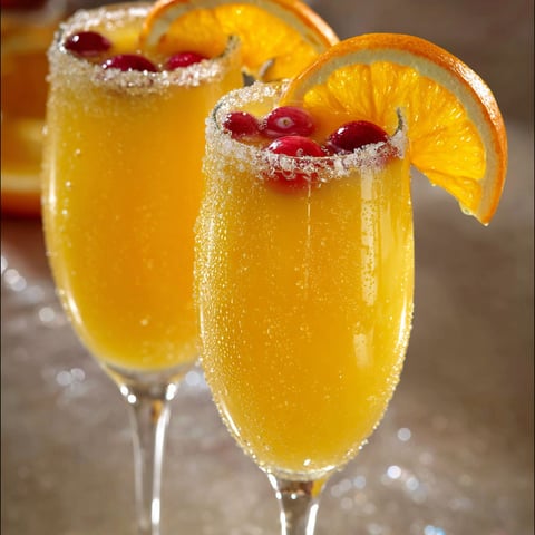 On voit des verres de punch de Noël faits maison, remplis d’une boisson colorée, décorée de fruits rouges et de rondelles de citron.