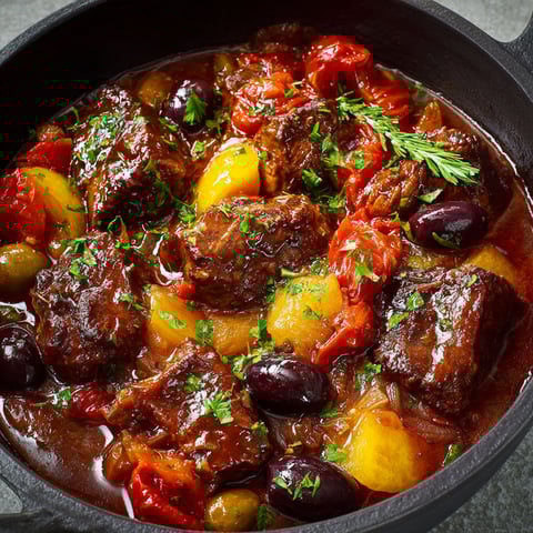 On voit une daube niçoise, bœuf mijoté servi bien chaud dans une cocotte noire.