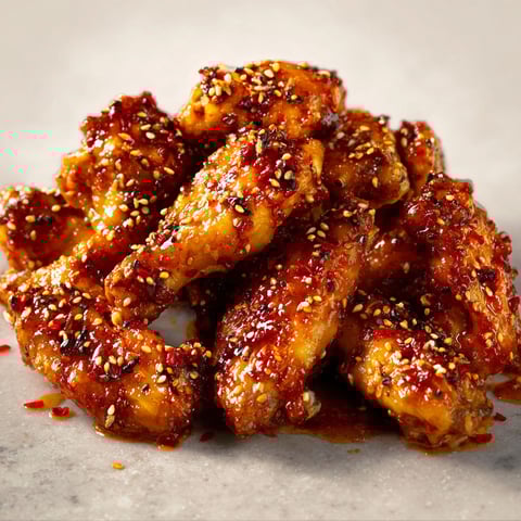 Sur le marbre, des ailes de poulet dorées au miel, citron et sésame, prêtes à être dégustées.